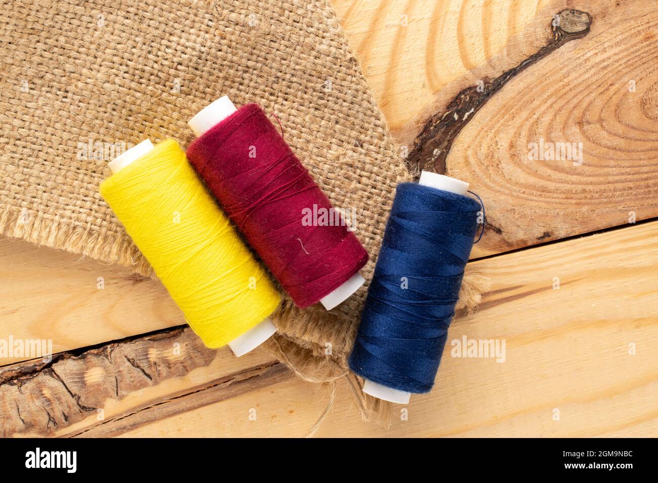 Several spools of colored thread, close-up, on a wooden table, top view. Stock Photo