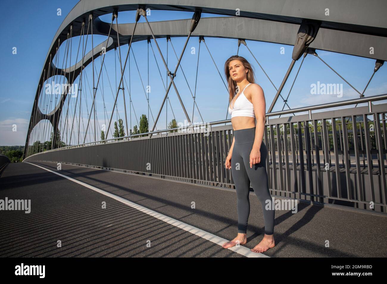 Young woman in yoga outfit on city street during sunny day in Frankfurt am Main, Hessen, Germany. Stock Photo