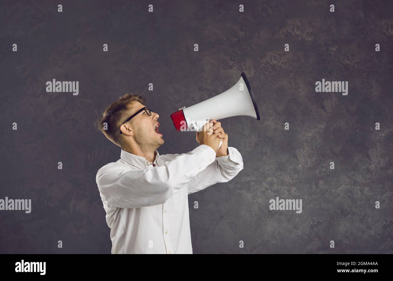 Serious young Caucasian male activist loudly makes loud announcement using loudspeaker. Stock Photo