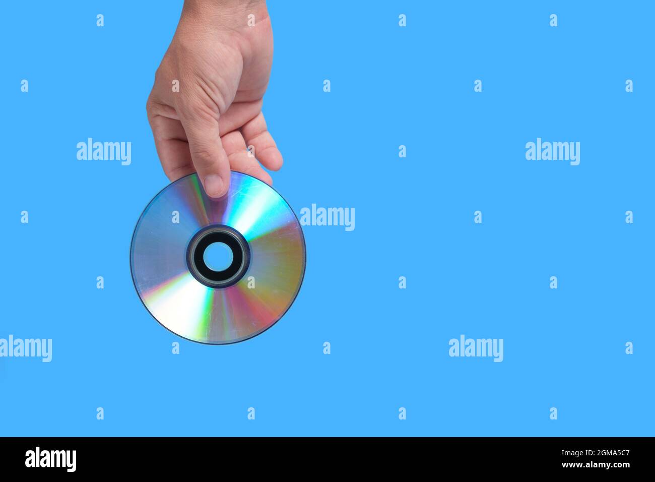 Scratched CD in your hand on a blue background, outdated technologies Stock Photo