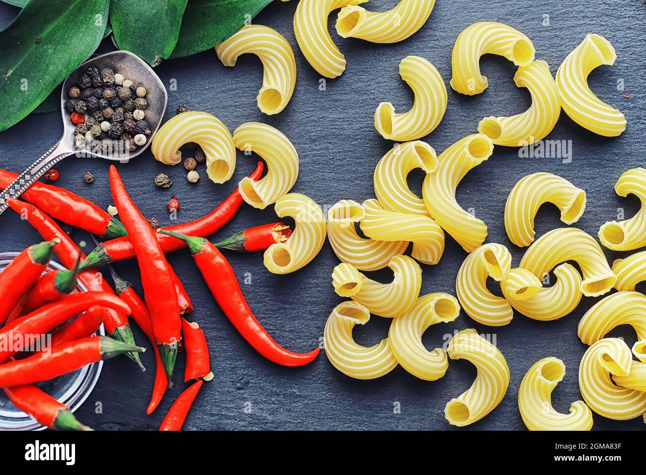 Uncooked pasta on a stone background. With seasonings and spices, spicy ...
