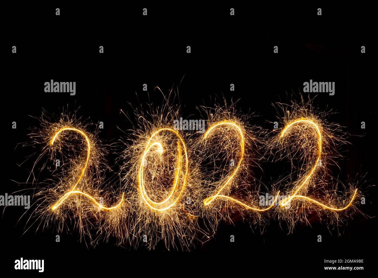 Happy New Year 2022. Number 2022 written sparkling sparklers isolated on black background with copy space for text. Glowing, creative overlay template Stock Photo