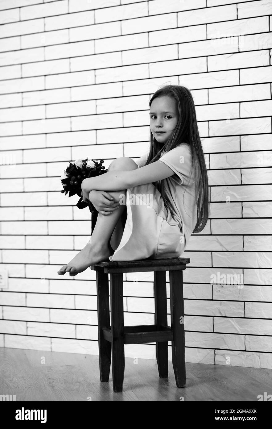 little girl is sitting on a chair and posing on the camera Stock Photo ...