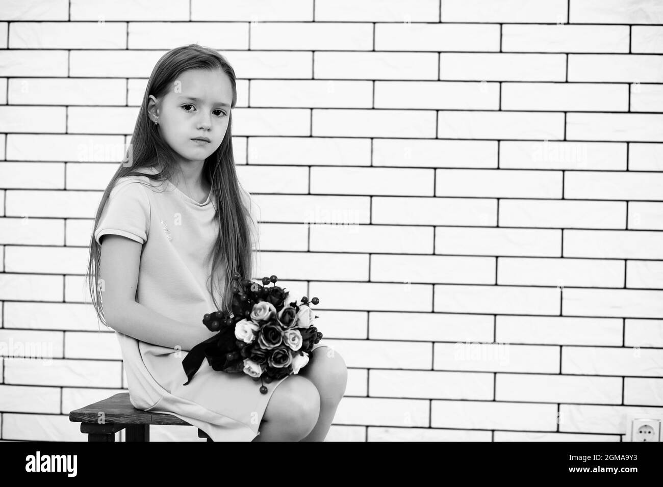little girl is sitting on a chair and posing on the camera Stock Photo ...