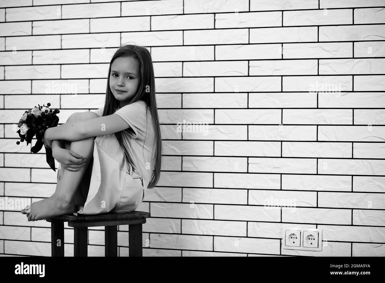 little girl is sitting on a chair and posing on the camera Stock Photo ...