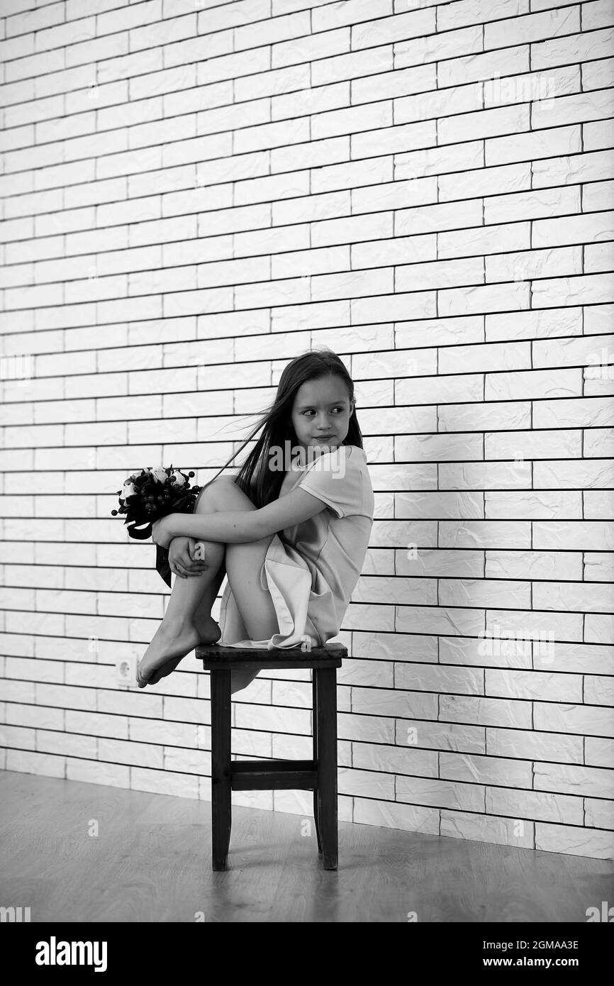 little girl is sitting on a chair and posing on the camera Stock Photo ...