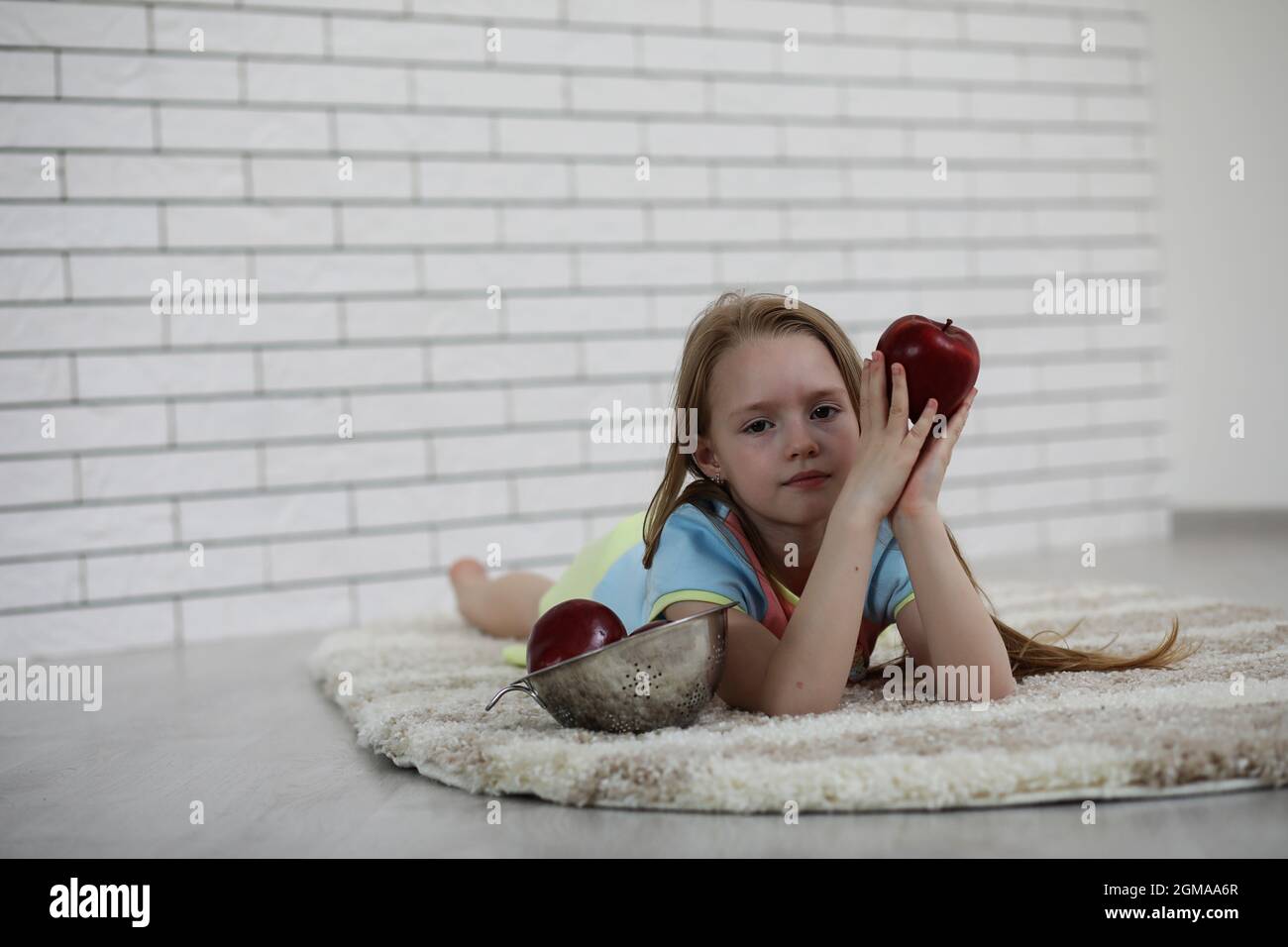 little girl lies on the floor and eats an apple Stock Photo - Alamy