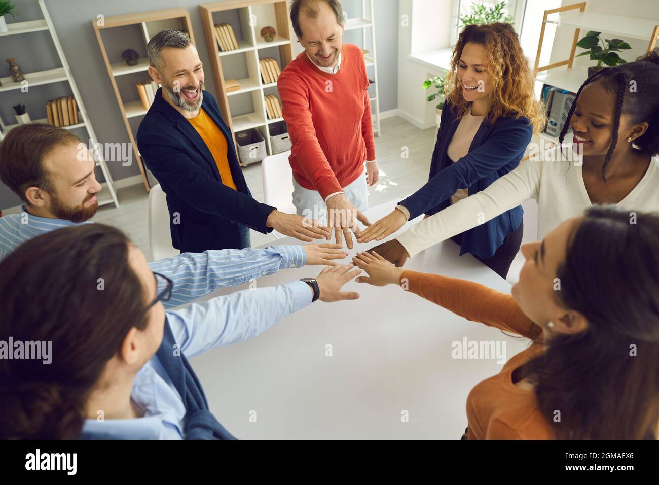Happy multi-ethnic people group join helping hands in circle together in office Stock Photo