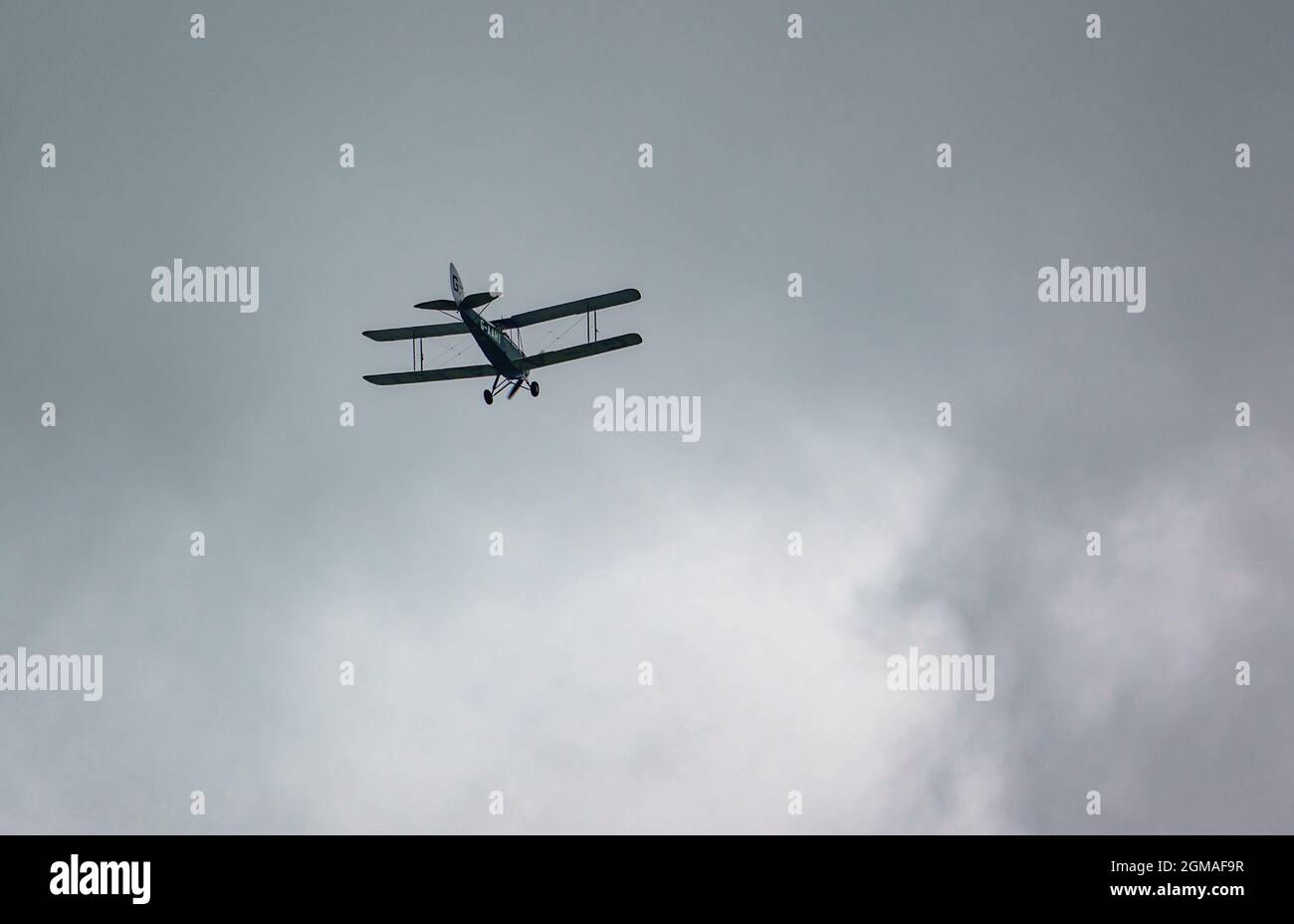 G-AAHI - a 1929 De Havilland DH-60G Gipsy Moth flying low and slow under cloud sky Stock Photo