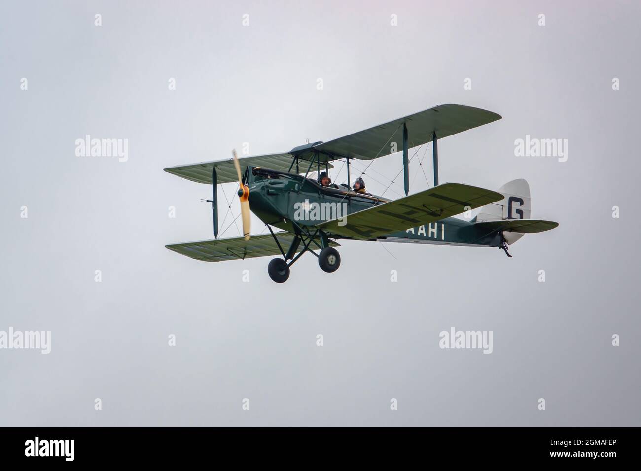 G-AAHI - a 1929 De Havilland DH-60G Gipsy Moth flying low and slow under cloud sky Stock Photo