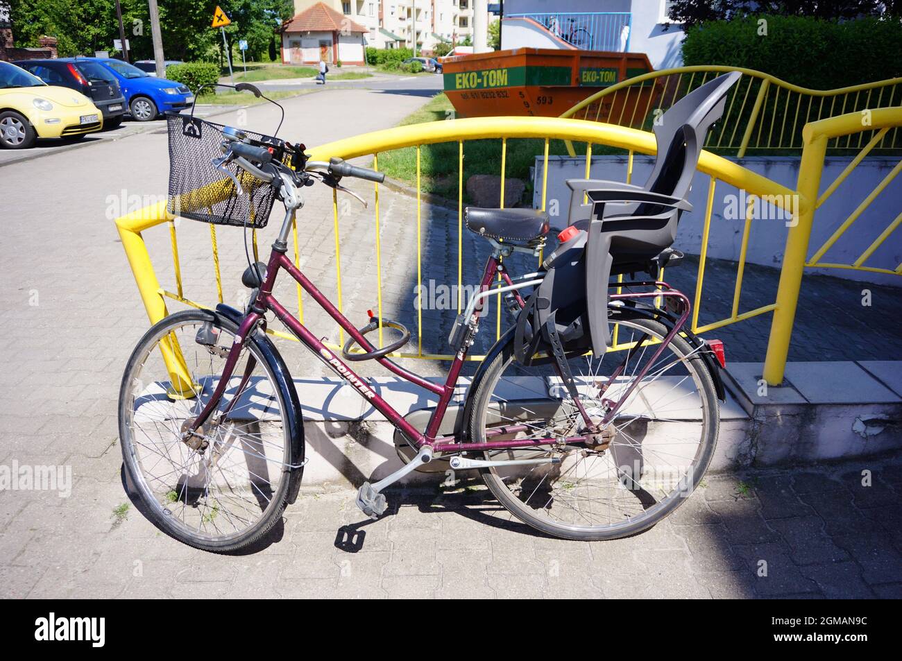 POZNAN, POLAND - May 20, 2018: A bicycle with a child's seat leaned on the yellow painted fence Stock Photo