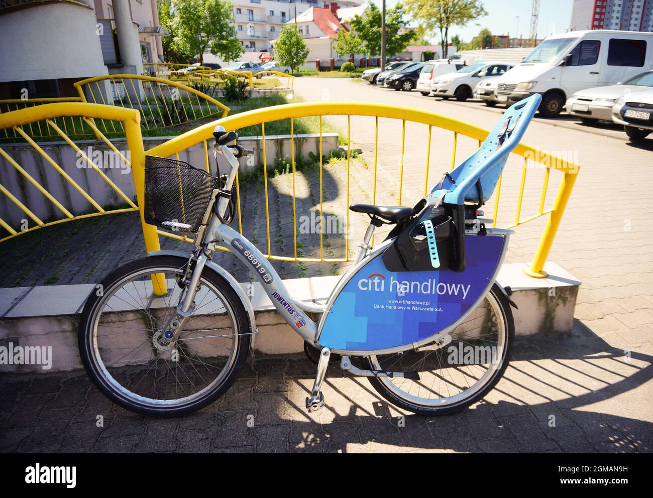 POZNAN, POLAND - May 20, 2018: A rental nextbike with a child's seat leaned on the painted yellow metal fence Stock Photo