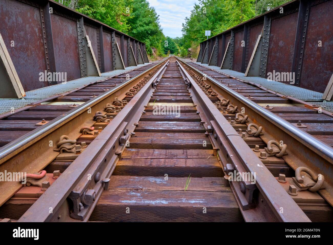 Railway tracks photographed from a low perspective crossing a rusty railroad bridge near Washago Ontario. Stock Photo