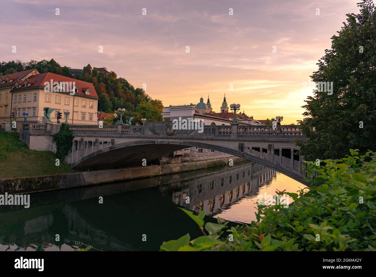 Dragon bridge in Ljubljana in sunset with Castle and cathedral background . Stock Photo