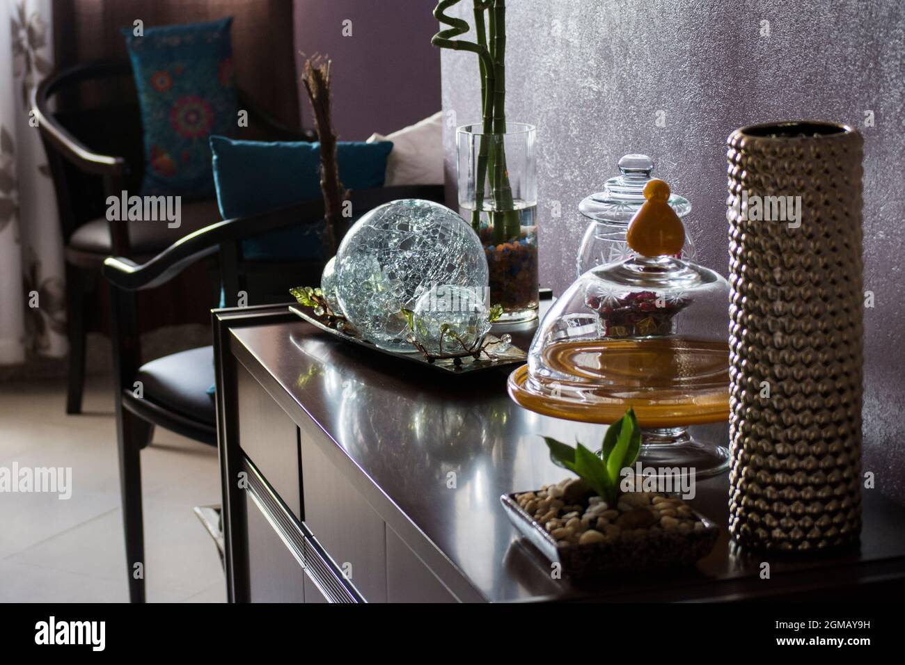 Interior of an apartment decorated with various objects made of glass, wood and plastic. Chairs, tables and pictures are part of the decoration. Stock Photo