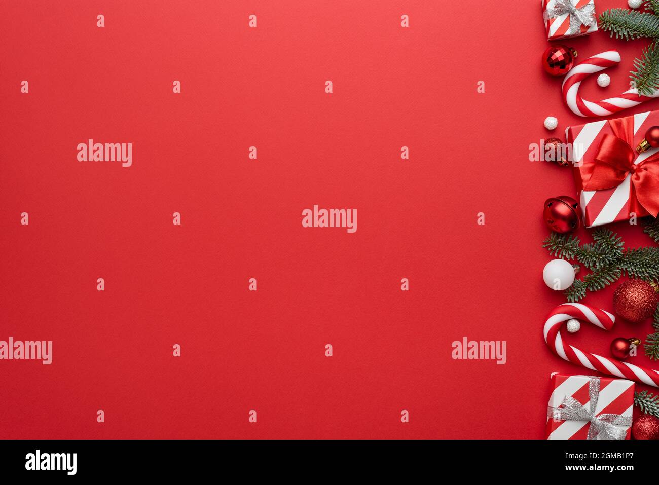 Holiday Christmas background with a frame made of decorated fir branches on red. Flat lay, top view and copy space for text Stock Photo