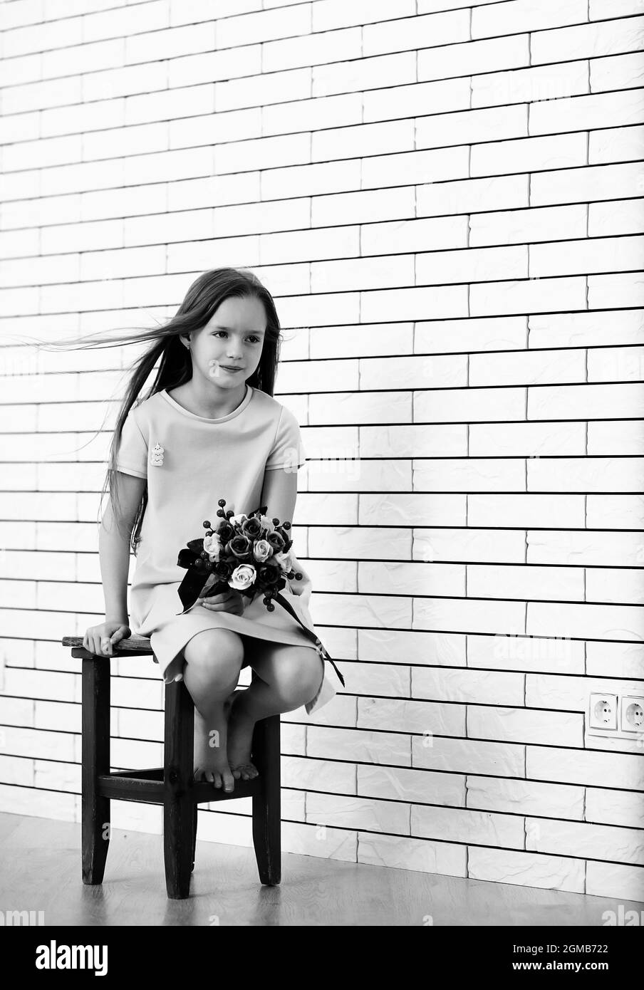 little girl is sitting on a chair and posing on the camera Stock Photo ...