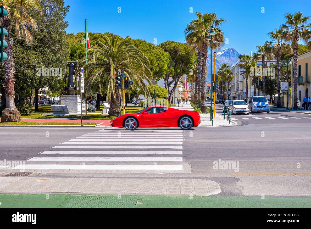 Red Ferrari sports class car passes on the coastal roads of a seaside vacation town in Tuscany, Forte dei Marmi, Versilia, Viareggio, Italy Stock Photo