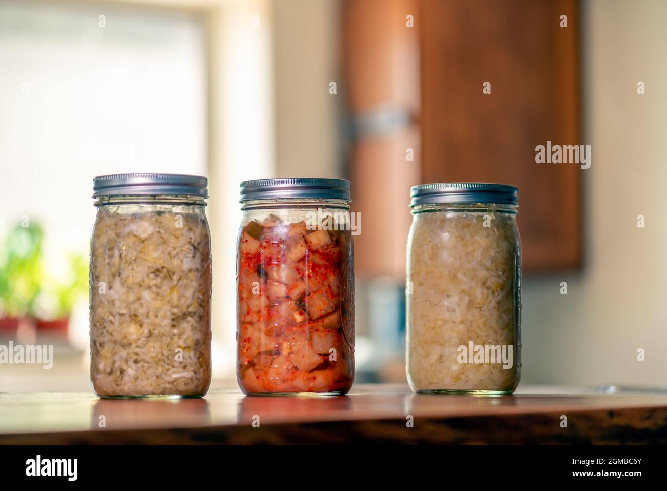 Sauerkraut, Dill kraut and kimchi in mason jars in home kitchen Stock Photo