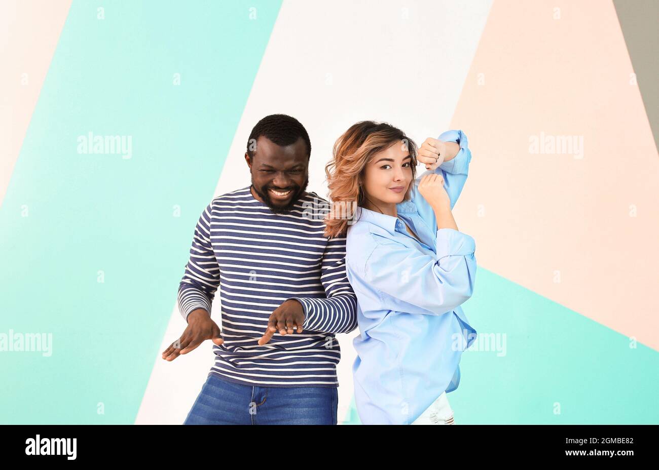 Cute interracial couple dancing against color wall Stock Photo - Alamy