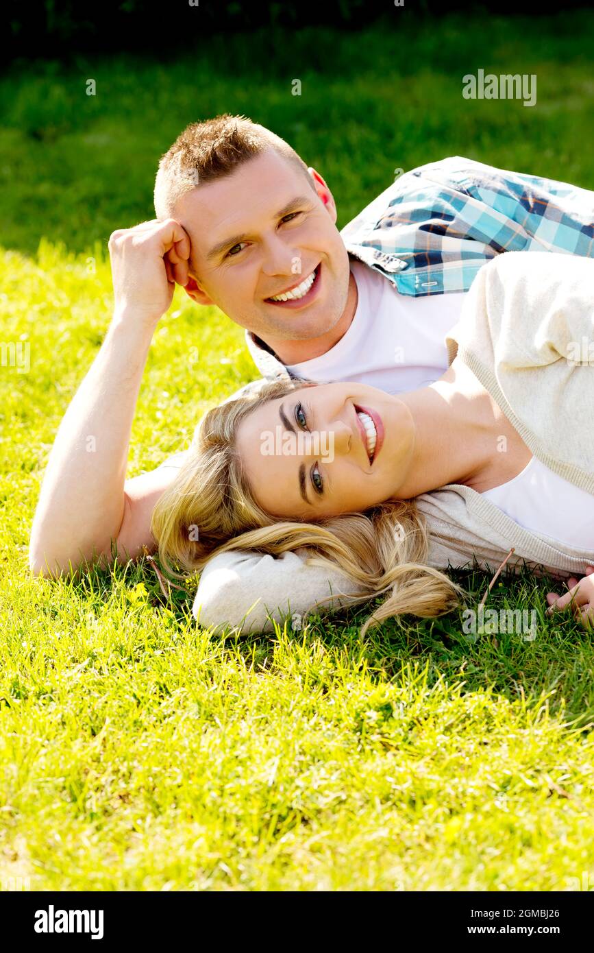 Romantic Caucasian couple lying in green grass Stock Photo - Alamy