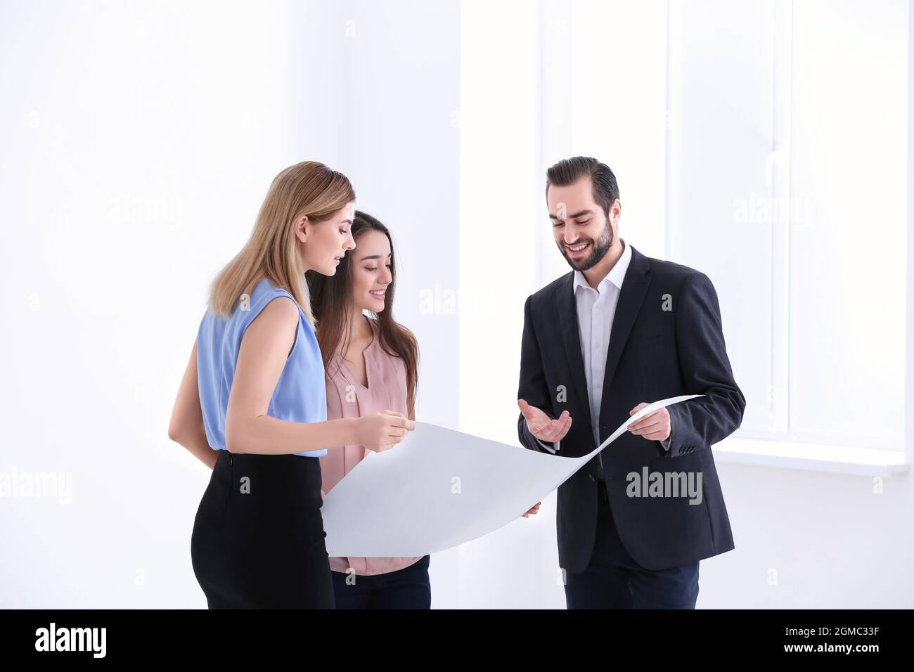 Real estate agent with trainee showing plan of apartment to client