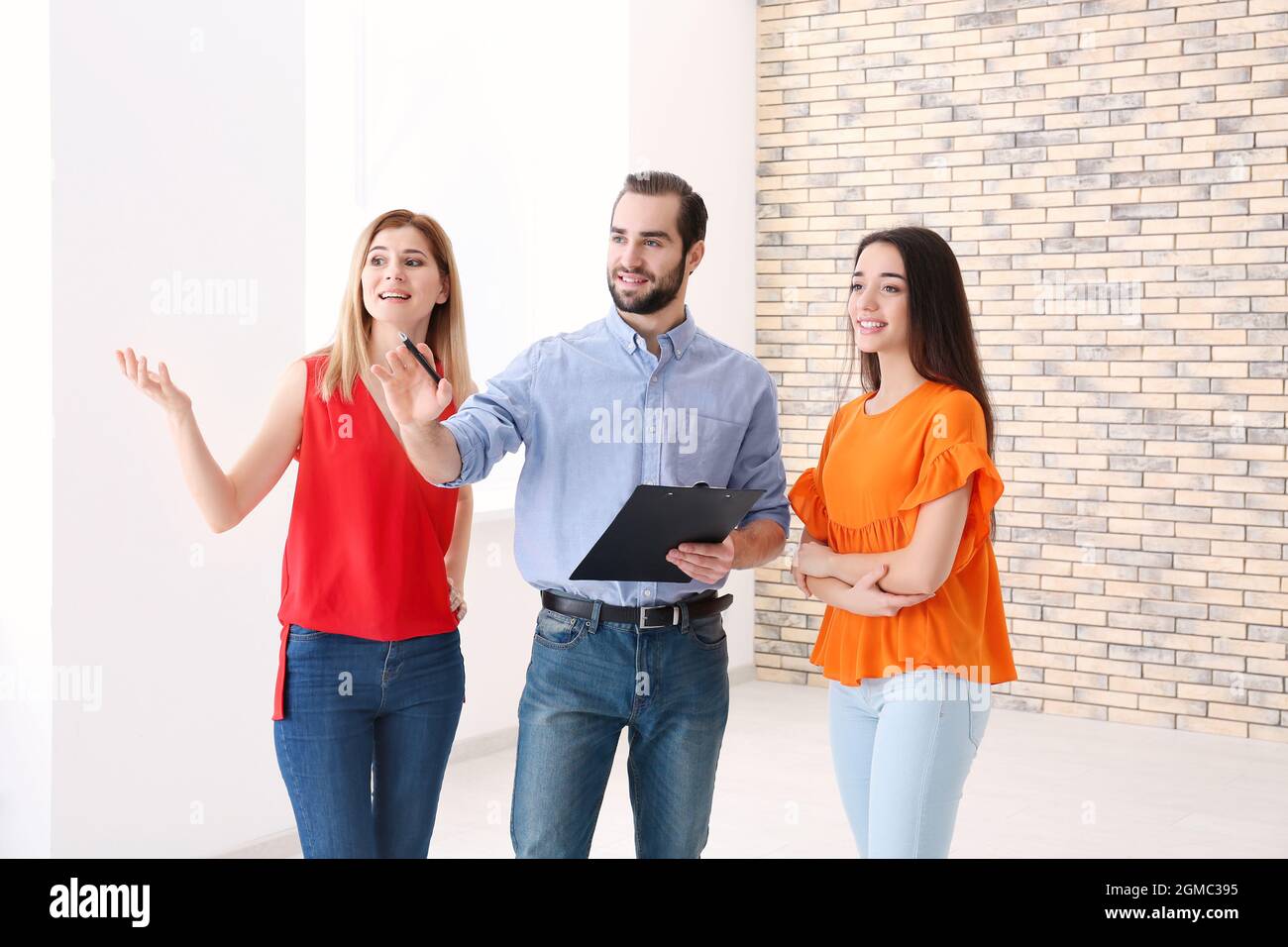 Real estate agent with trainee showing apartment to client Stock Photo
