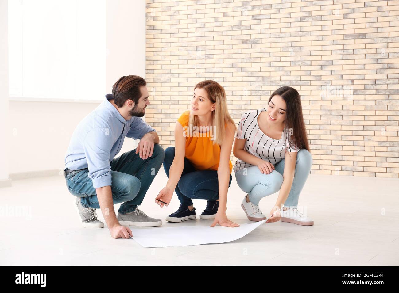 Real estate agent with trainee showing plan of apartment to client