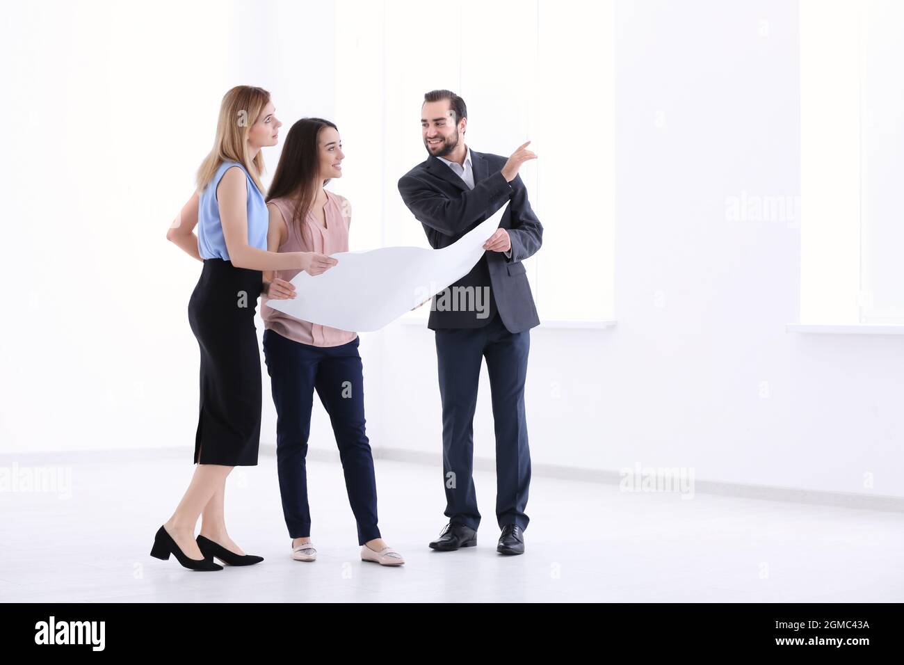 Real estate agent with trainee showing plan of apartment to client