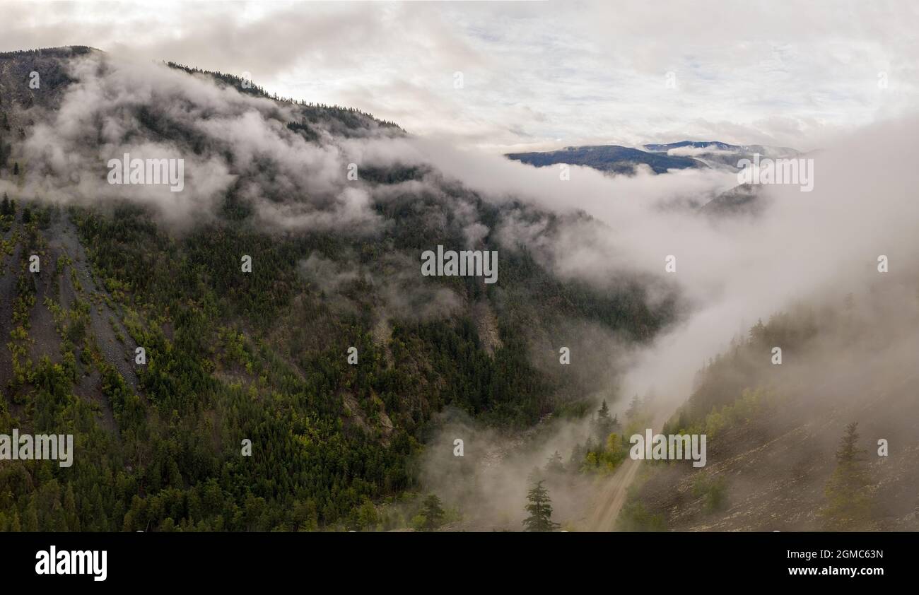 Aerial panorama view of the breathtaking mountainous landscape in Tweedsmuir (South) Provincial Park in a dense fog that is covering the surrounding m Stock Photo