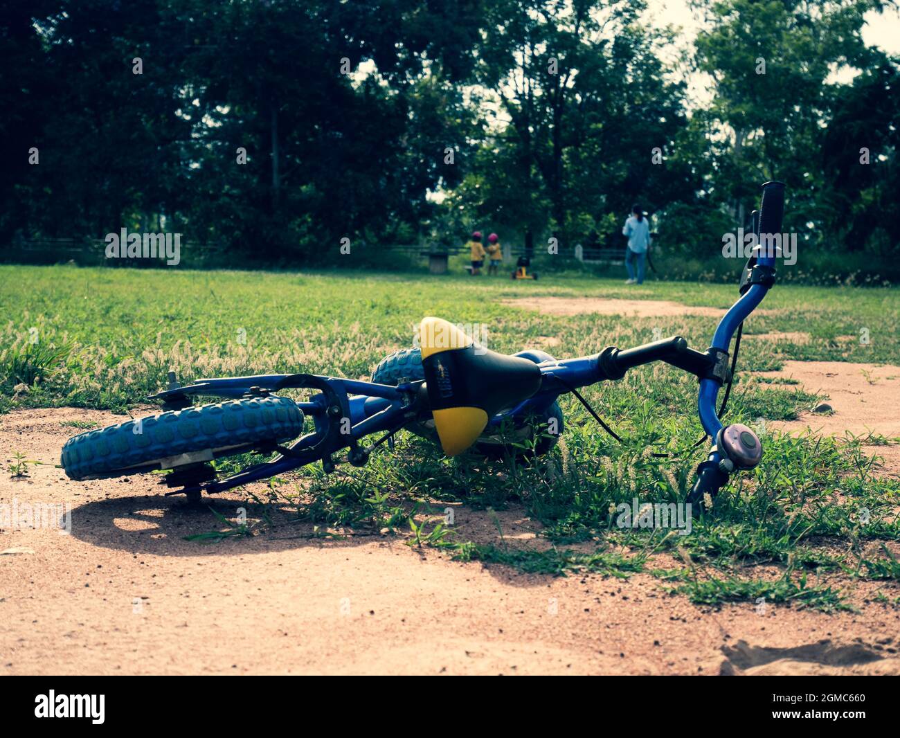 Balance bike lying on the grass in the summer park. Falling off a bike on a sunny day. Stock Photo