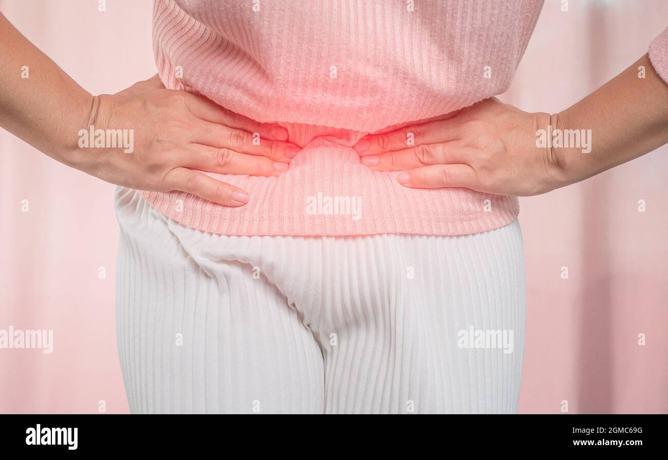 Young sick woman with hands holding her belly suffering menstrual period pain at home. Gynecology and female health concept. Stock Photo