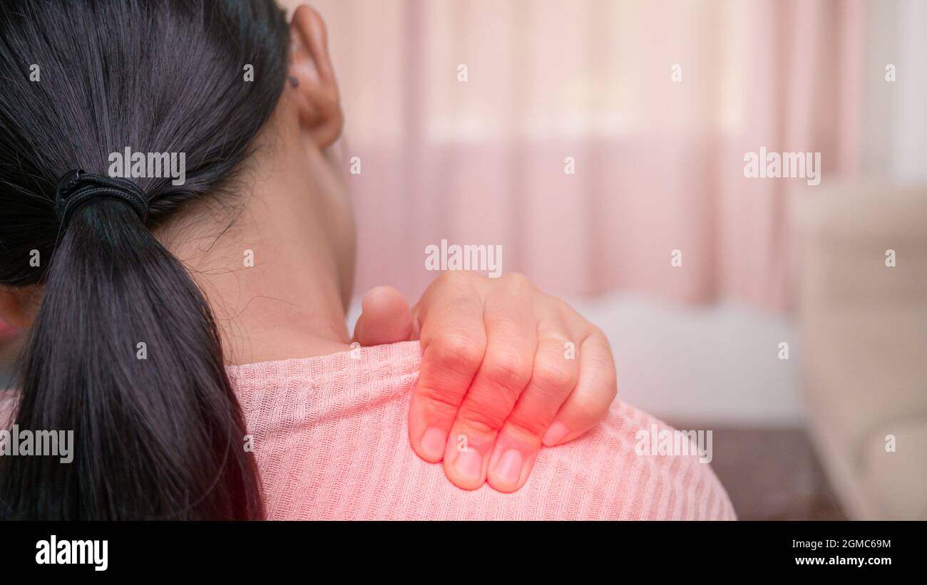 Close up of female massaging her painful shoulder caused by prolonged work on the computer or phone. Neck, trapezoid and shoulders pain. Muscle spasm. Stock Photo