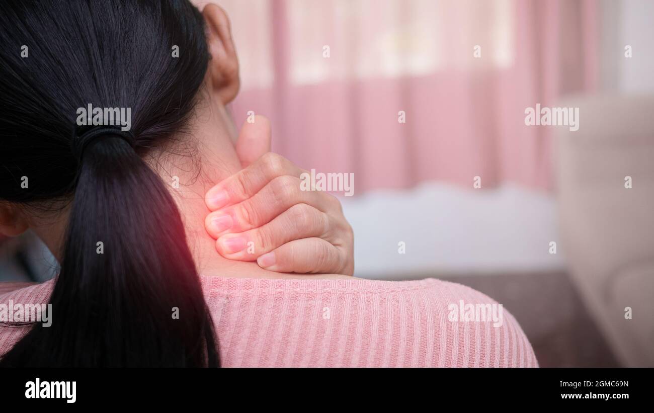 Close up of female massaging her painful neck caused by prolonged work on the computer or phone. Neck, trapezoid and shoulders pain. Muscle spasm. Stock Photo