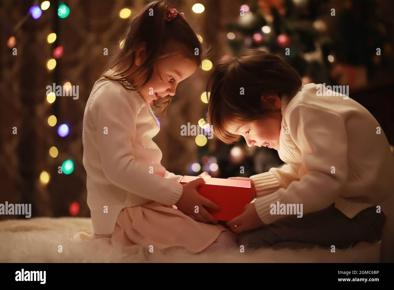 Family on Christmas eve at fireplace. Kids opening Xmas presents Christmas Eve Traditiona