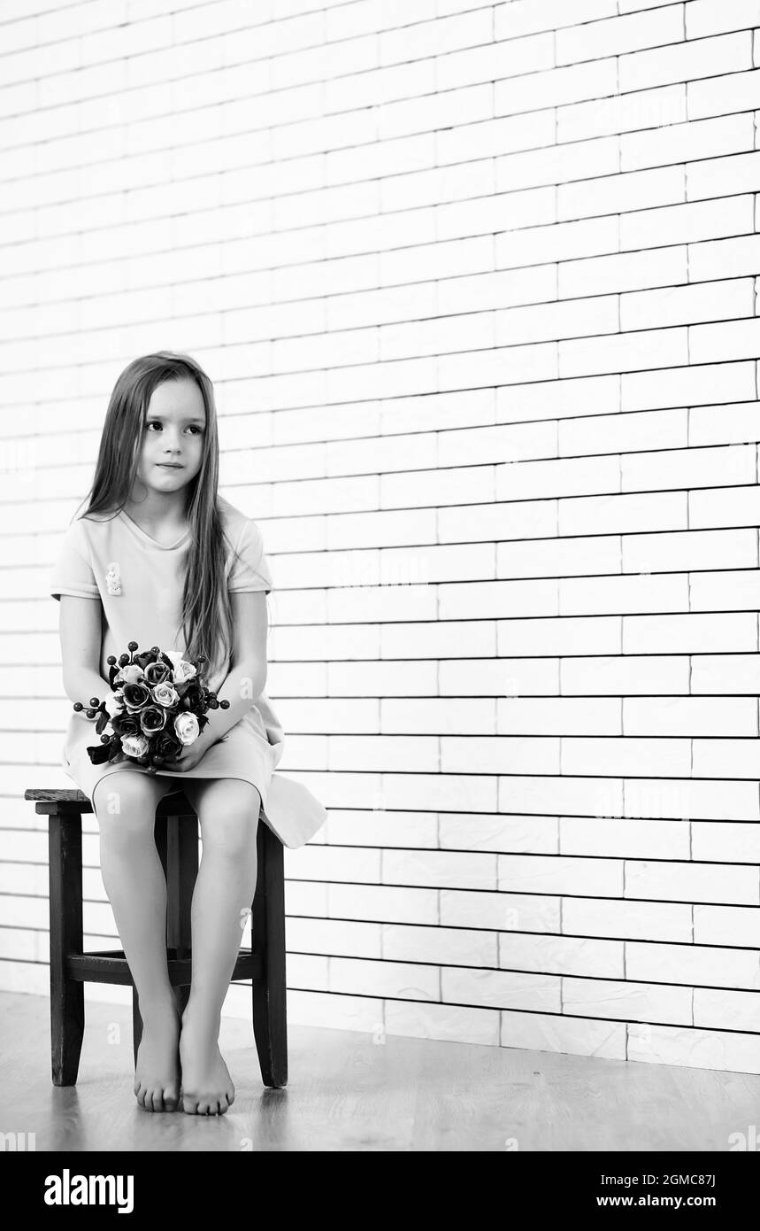 little girl is sitting on a chair and posing on the camera Stock Photo ...