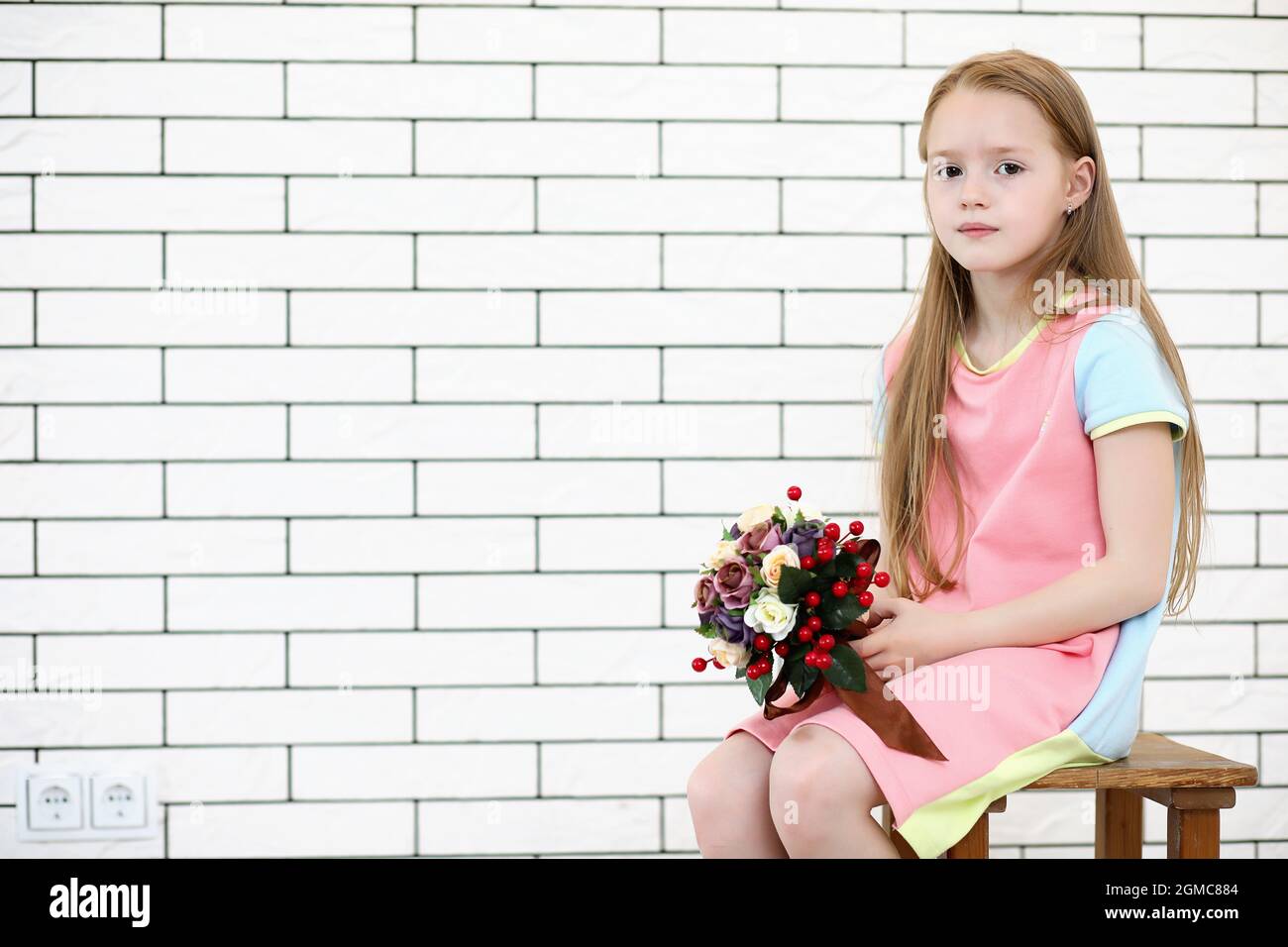 little girl is sitting on a chair and posing on the camera Stock Photo ...
