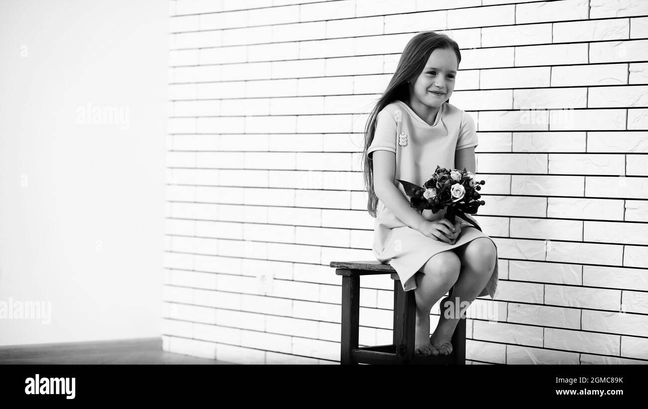 little girl is sitting on a chair and posing on the camera Stock Photo ...