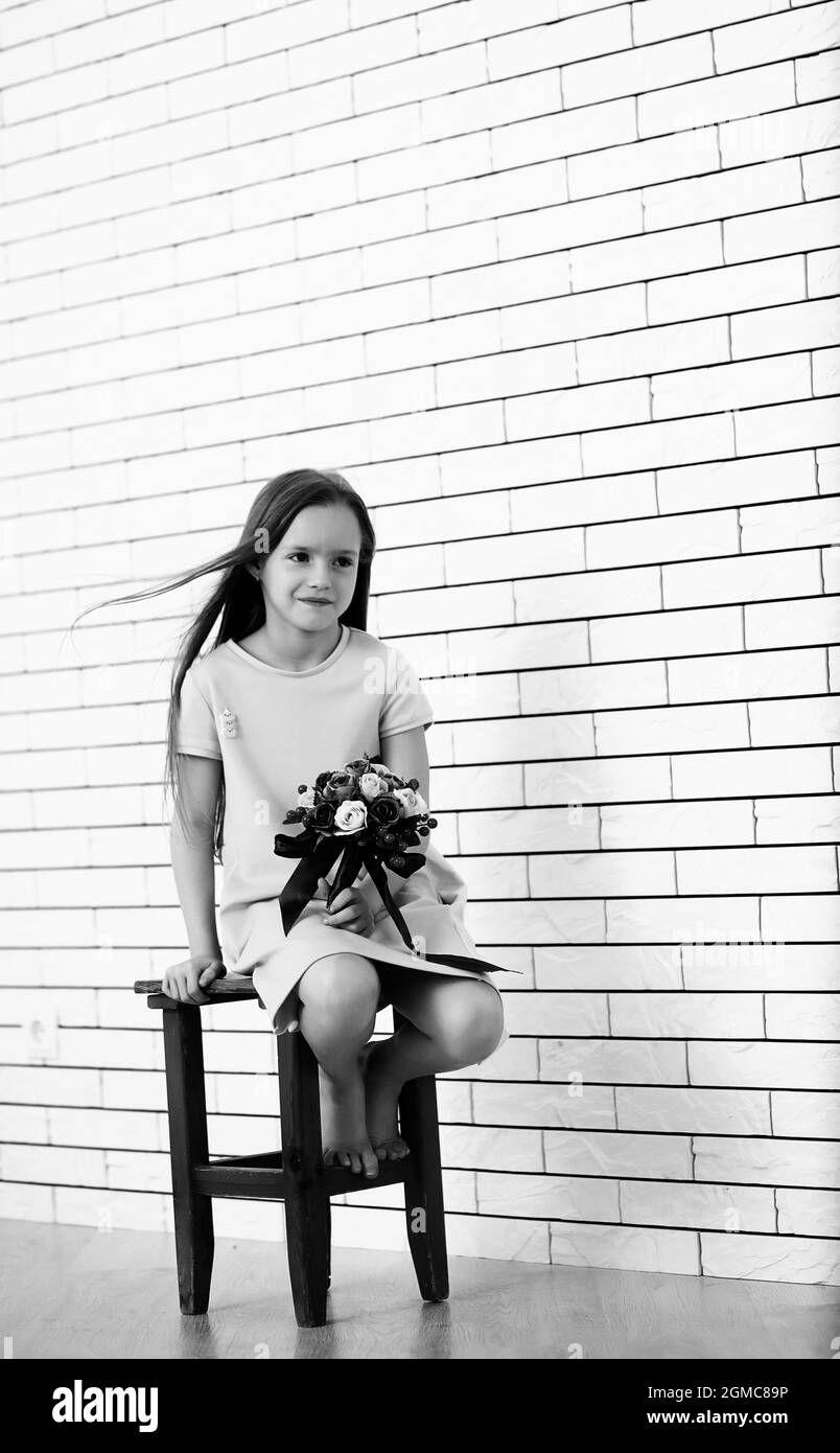 little girl is sitting on a chair and posing on the camera Stock Photo ...