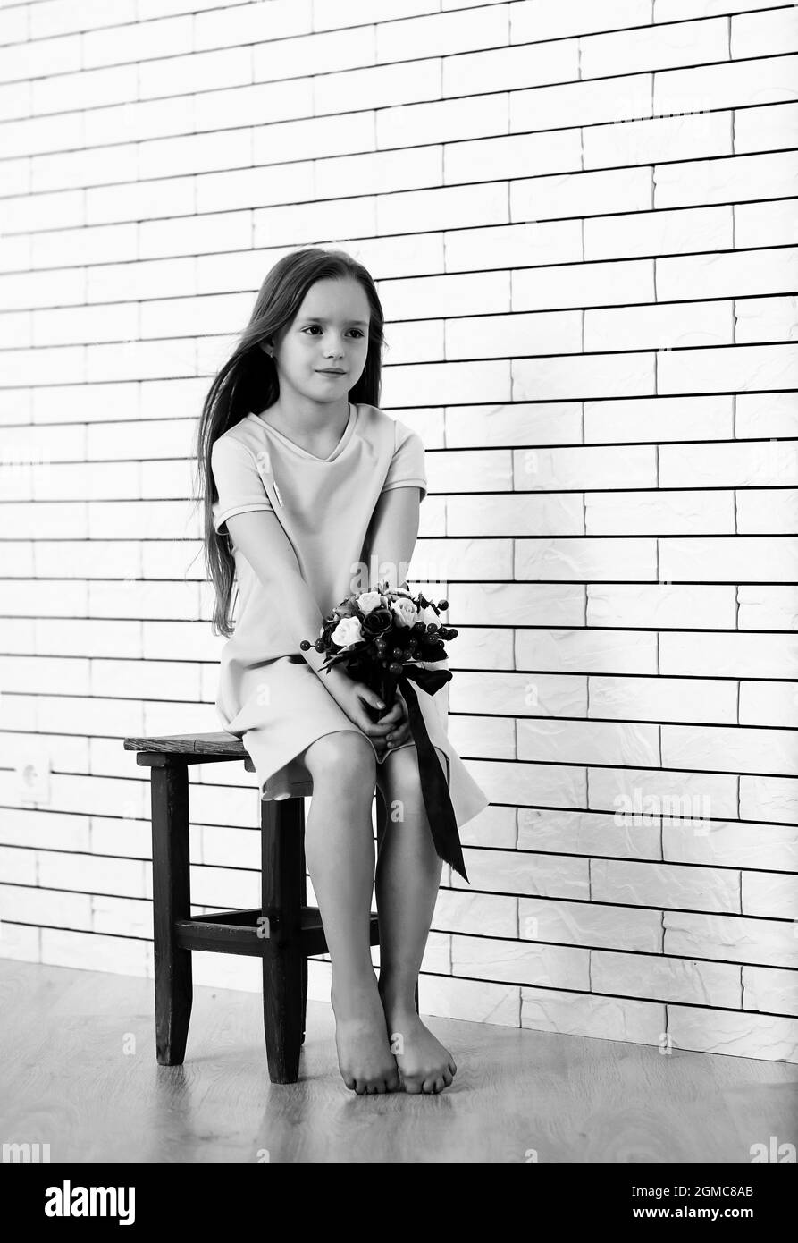 little girl is sitting on a chair and posing on the camera Stock Photo ...
