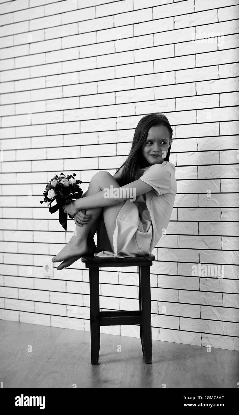little girl is sitting on a chair and posing on the camera Stock Photo ...