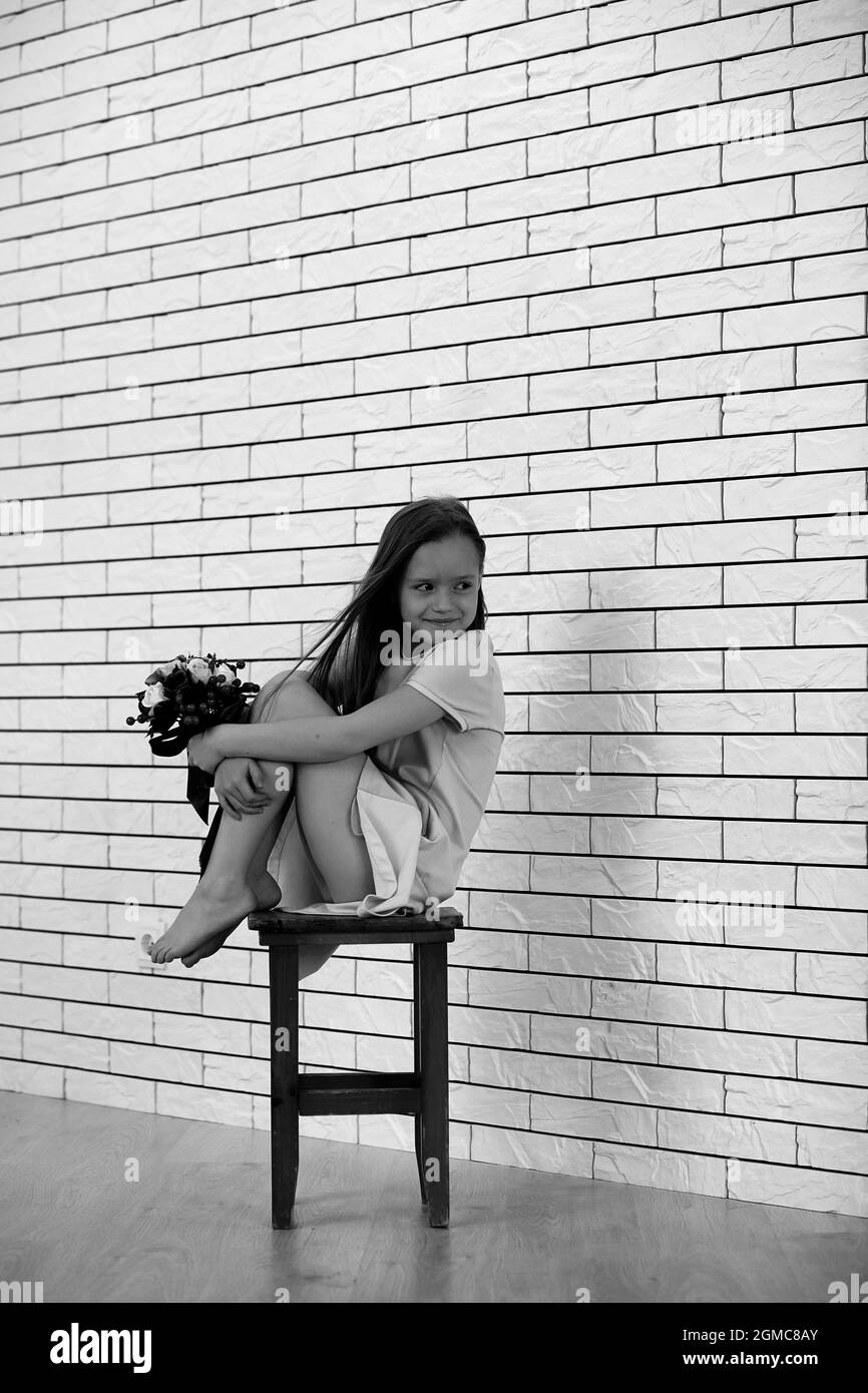 little girl is sitting on a chair and posing on the camera Stock Photo ...