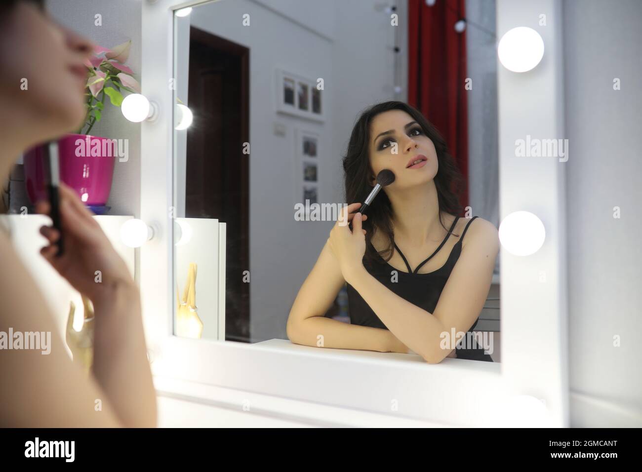 Beautiful girl doing makeup in front of a mirror Stock Photo - Alamy