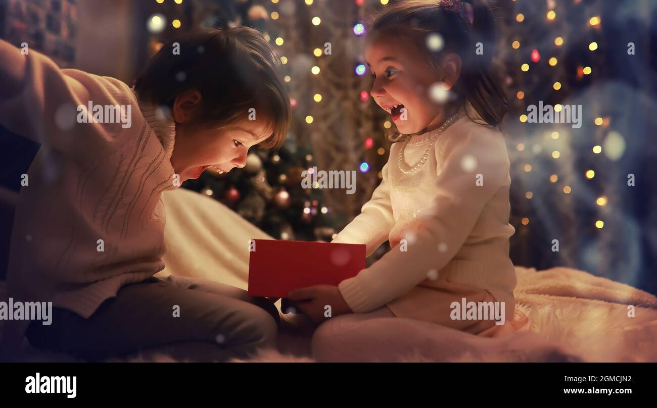 Family on Christmas eve at fireplace. Kids opening Xmas presents Christmas Eve Traditiona