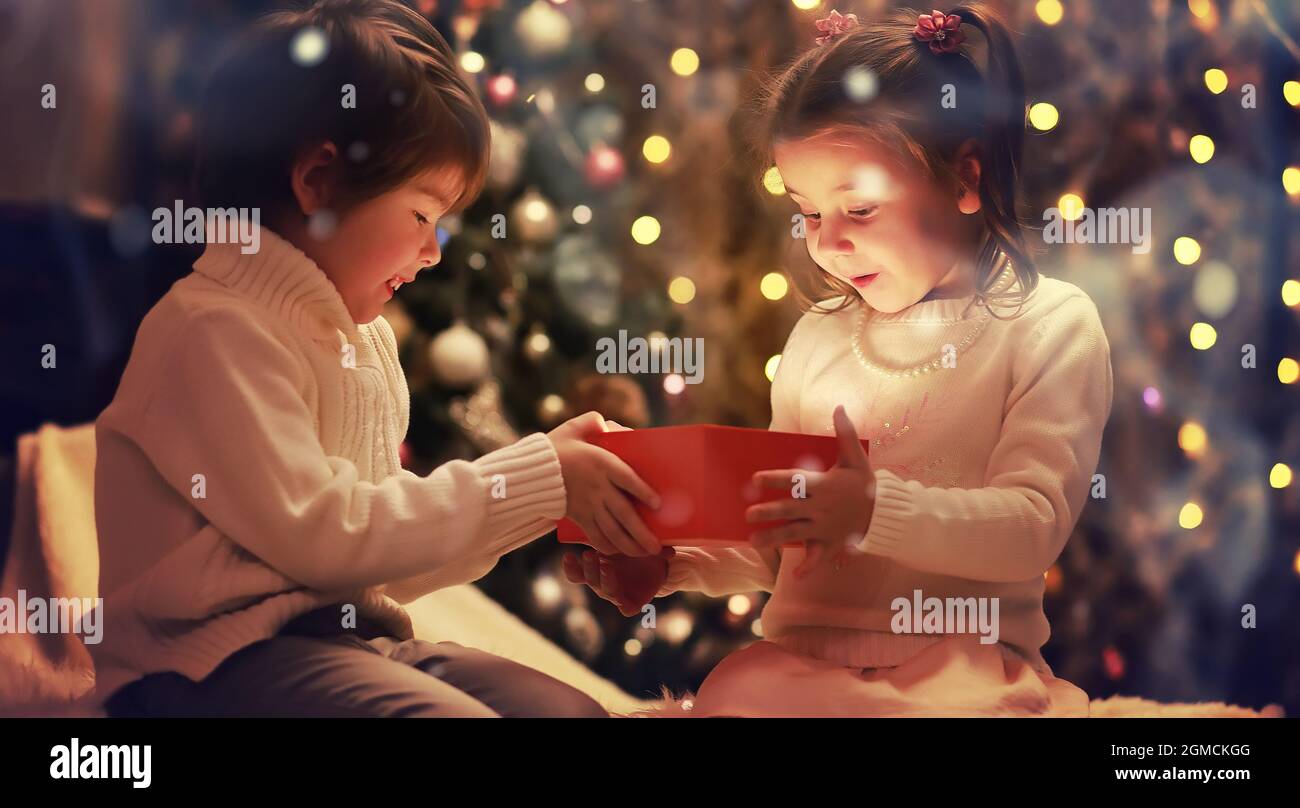 Family on Christmas eve at fireplace. Kids opening Xmas presents
