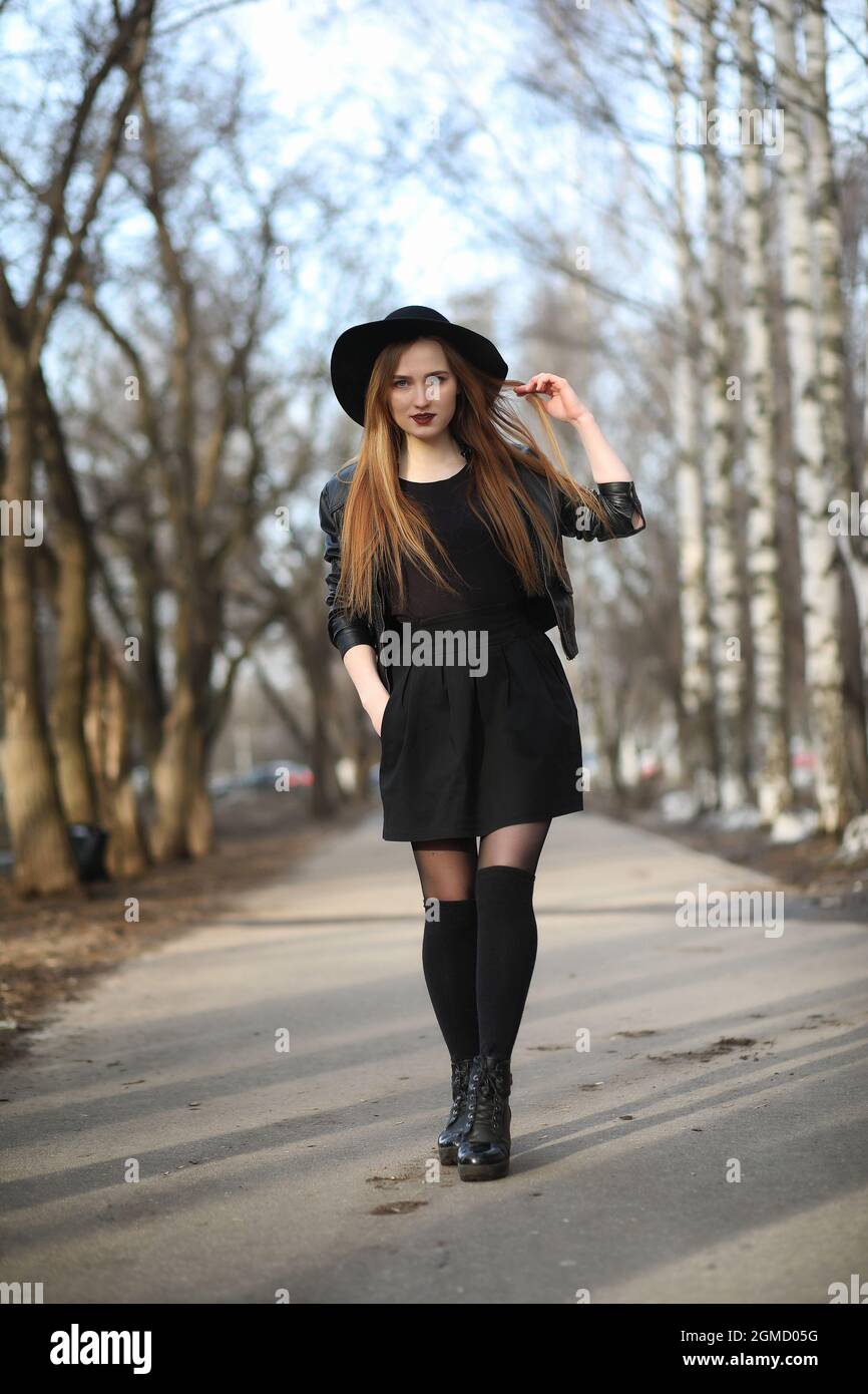 A girl walks down the city street in a leather waistcoat with a