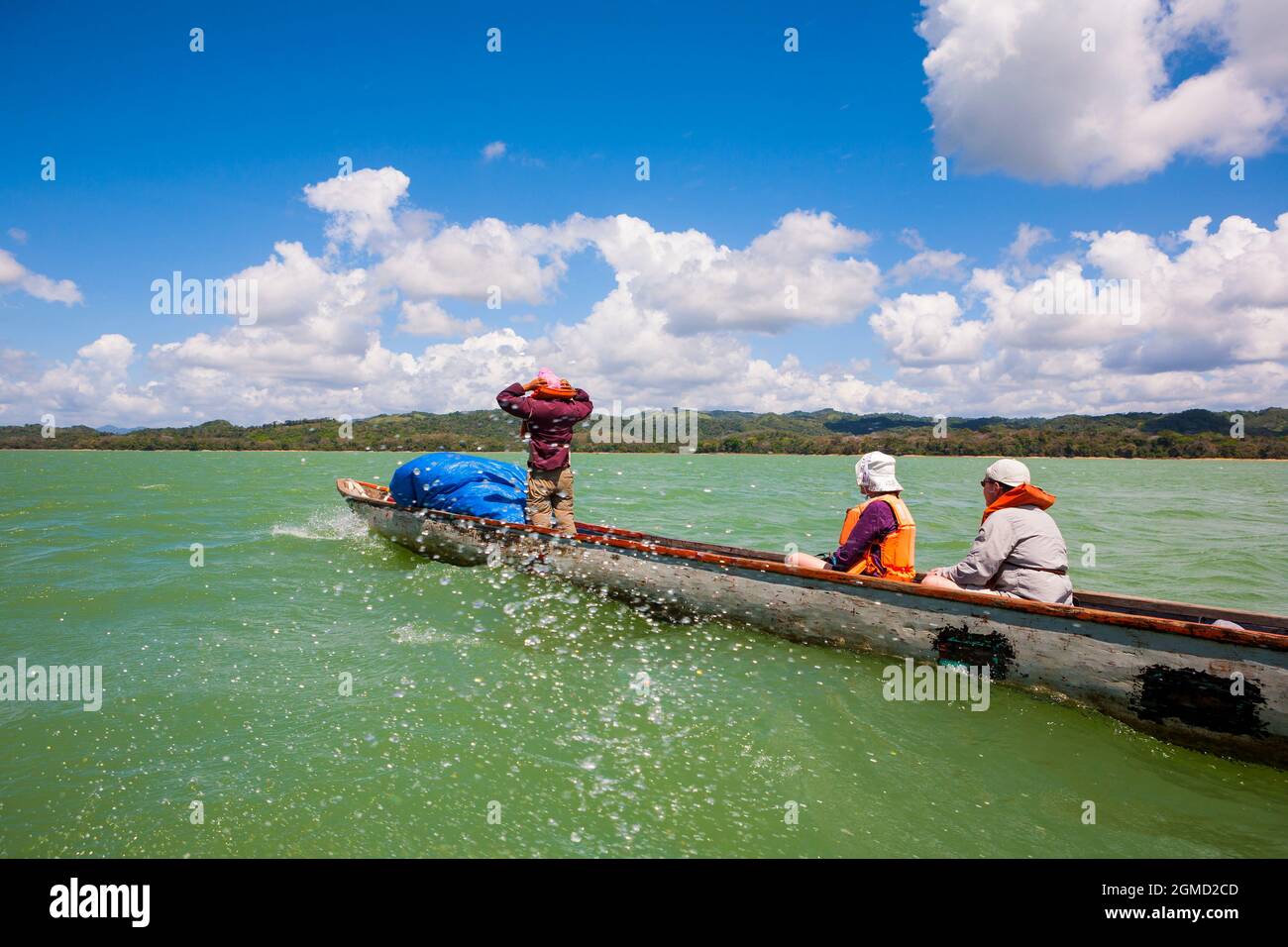 A dugout canoe with three adventurers is crossing Alajuela lake, Panama province, Republic of Panama, Central America. Stock Photo