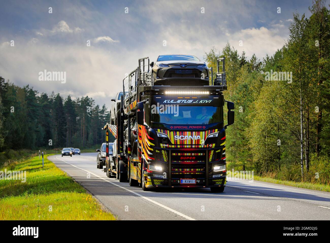 Unique vehicle carrier Scania R650 of Kuljetus J. Kivi transports new cars on road 25, high beams on briefly. Raasepori, Finland. September 9, 2021. Stock Photo