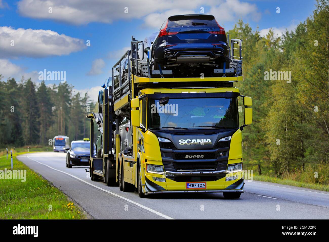 Yellow Scania P500 car carrier truck transports new vehicles on road 25 on a sunny day of autumn. Raasepori, Finland. September 9, 2021. Stock Photo