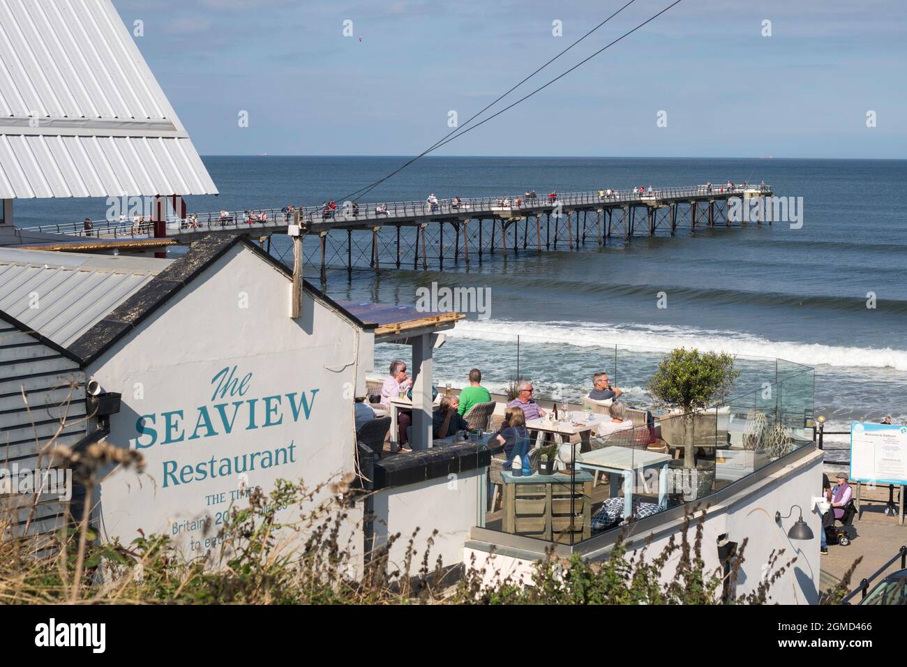 People sitting outside the Seaview Restaurant with Saltburn pier in the background, North Yorkshire, England, UK Stock Photo